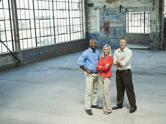 Business people smiling in empty warehouse - BLEF06876