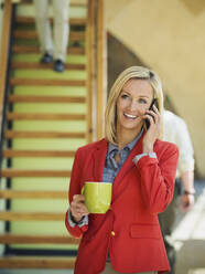 Geschäftsfrau, die in der Nähe einer Treppe mit einem Handy telefoniert - BLEF06878