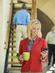 Geschäftsfrau benutzt Mobiltelefon in der Nähe der Treppe - BLEF06879