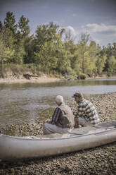 Caucasian father and son sitting in canoe on riverbed - BLEF06890