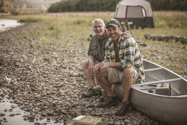 Caucasian father and son sitting in canoe at campsite - BLEF06893