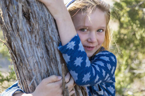 Kaukasisches Mädchen umarmt Baum im Freien - BLEF06906
