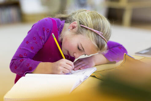 Kaukasisches Mädchen schreibt im Klassenzimmer - BLEF06912