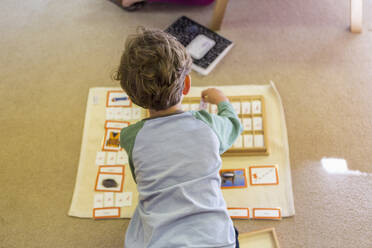 Kaukasischer Junge ordnet Karten im Klassenzimmer - BLEF06916