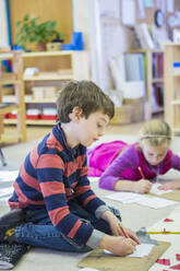 Kaukasische Kinder schreiben im Klassenzimmer - BLEF06936