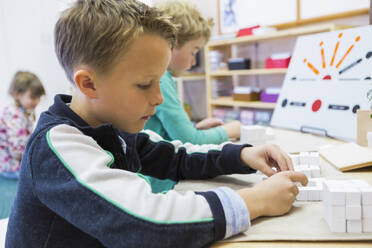 Nahaufnahme eines Jungen, der im Klassenzimmer ein Rätsel löst - BLEF06938