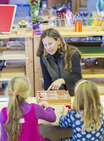 Montessori-Lehrer hilft Schülern im Klassenzimmer, lizenzfreies Stockfoto