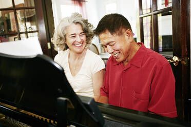 Couple playing piano together in living room - BLEF06984