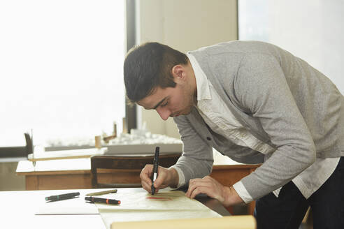 Kaukasischer Geschäftsmann schreibt am Schreibtisch im Büro - BLEF07029