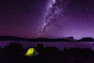 Milky Way galaxy over campsite in starry night sky - MINF12340