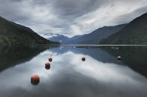 Buoys floating in still remote lake under clouds - MINF12347