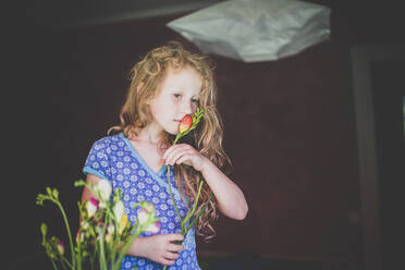 Girl smelling at a flower - IHF00106