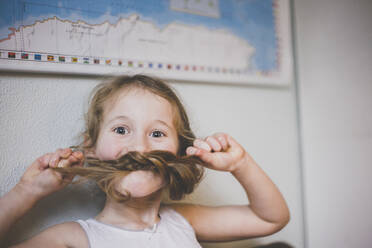 Porträt eines Mädchens, das mit seinen langen Haaren spielt und sich mit seinen Zöpfen einen Schnurrbart macht - IHF00113
