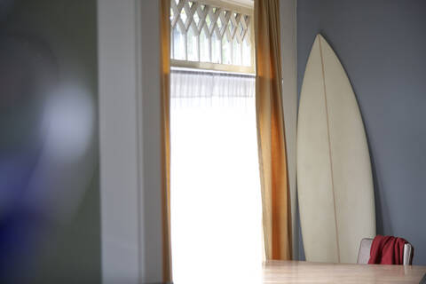 Surfbrett und Tisch am Fenster, lizenzfreies Stockfoto