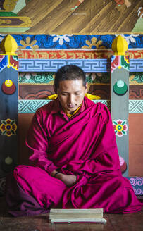 Asiatischer Mönch liest auf dem Tempelboden - MINF12443