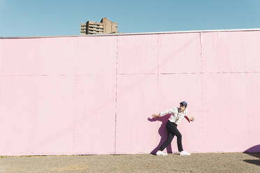 Young man in front of pink construction barrier, traying to escape - UUF17862