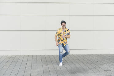 Young man wearing flat hat and aloha shirt, having fun - UUF17868