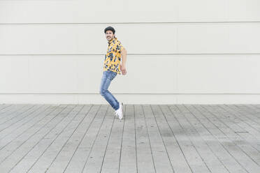 Young man wearing flat hat and aloha shirt, having fun - UUF17871