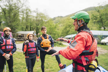 Instructor talking to group of friends at a rafting class - FBAF00725