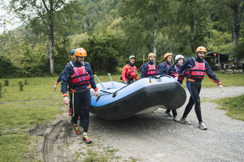 Eine Gruppe von Freunden bereitet sich auf eine Rafting-Tour mit einem Schlauchboot vor - FBAF00730