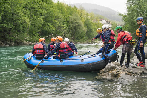 Gruppe von Personen, die eine Rafting-Tour in einem Schlauchboot auf einem Fluss beginnen - FBAF00732