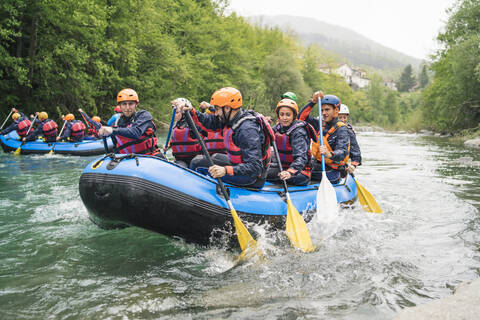 Gruppe von Menschen beim Rafting im Schlauchboot auf einem Fluss, lizenzfreies Stockfoto