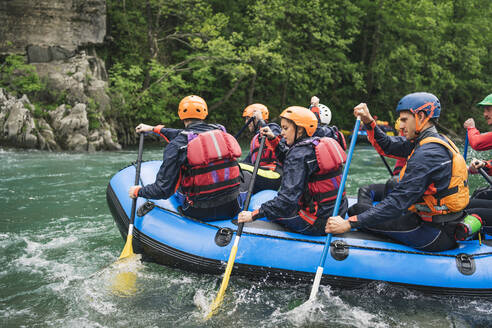 Group of people rafting in rubber dinghy on a river - FBAF00737