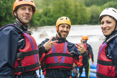 Glückliche Freunde bei einem Raftingkurs posieren am Flussufer, lizenzfreies Stockfoto