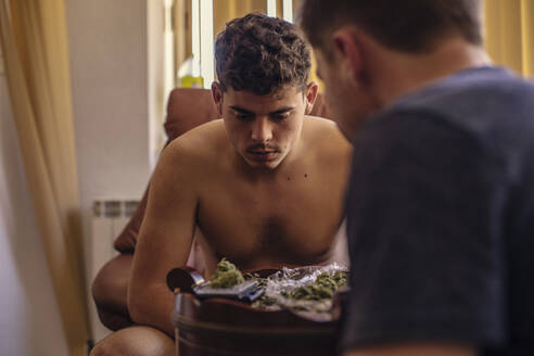 Zwei junge Männer im Wohnzimmer betrachten Marihuana-Knospen - ACPF00539