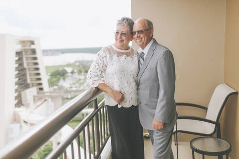 Lächelndes gekleidetes älteres Paar auf Balkon stehend - CMSF00065