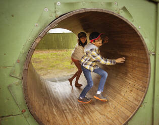 Mixed race children playing in wheel in playground - BLEF07053