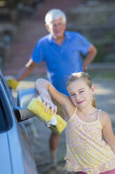 Kaukasischer Großvater und Enkelin waschen Auto im Freien - BLEF07058
