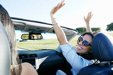 Excited women driving convertible on road trip - BLEF07064