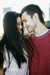 Lächelndes, sich umarmendes Paar auf einem städtischen Hausdach - BLEF07084
