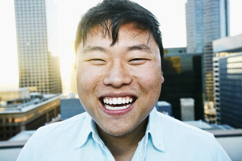 Koreanischer Mann lächelnd auf dem Dach einer Stadt, lizenzfreies Stockfoto