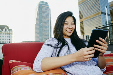 Chinesische Frau benutzt digitales Tablet auf einem Hausdach - BLEF07088