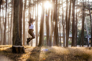 Schwarze Frau springt von Baumstumpf in sonnigem Wald - BLEF07108