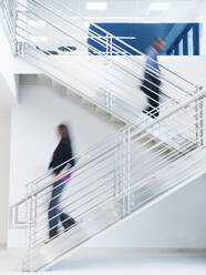 Blurred view of business people climbing office staircase - BLEF07116