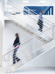 Unscharfe Ansicht von Geschäftsleuten, die eine Bürotreppe hinaufsteigen - BLEF07116