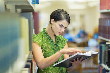 Mixed race student reading book in library - BLEF07173