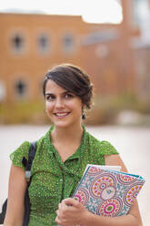 Gemischtrassiger Student trägt Bücher auf dem Campus - BLEF07180