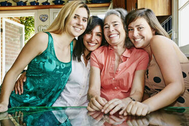 Caucasian mother and daughters hugging in kitchen - BLEF07183