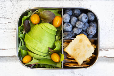 Lunchbox with salad, avocado and yellow tomato, cracker, and blueberry, from above - LVF08101