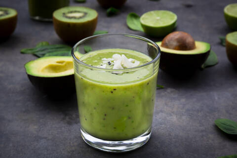 Grüner Smoothie mit Avocado, Spinat, Kiwi und Limette, Kokosnussflocken und schwarzem Sesam, lizenzfreies Stockfoto