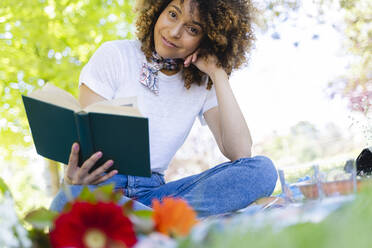 Porträt einer entspannten Frau, die im Park ein Buch liest - FMOF00692