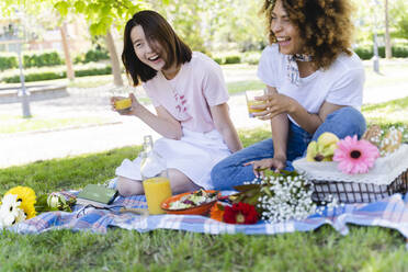 Two laughing women having a picnic in park - FMOF00706