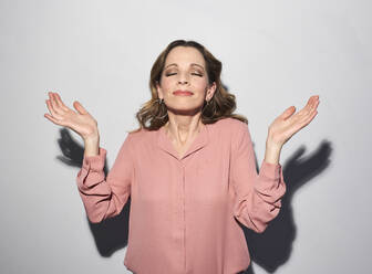 Portrait of brunette woman with closed eyes raising her arms - PNEF01607