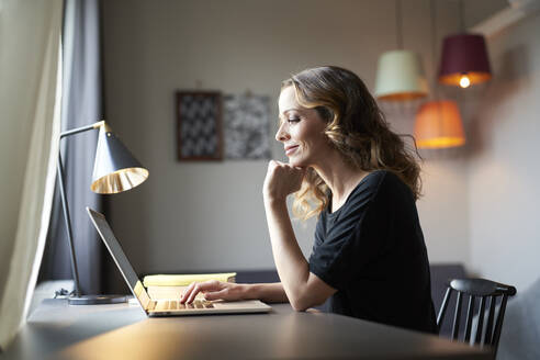 Woman using laptop at table at home - PNEF01615