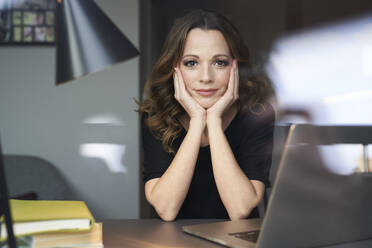 Portrait of woman with laptop behind windowpane - PNEF01623