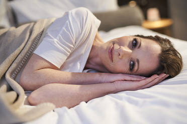 Portrait of content woman lying in bed - PNEF01658